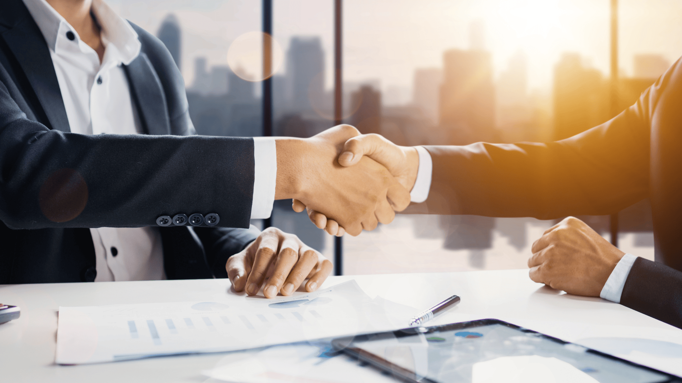 two business people shaking hands at a desk representing the powerful partnership between your business and your managed IT partner